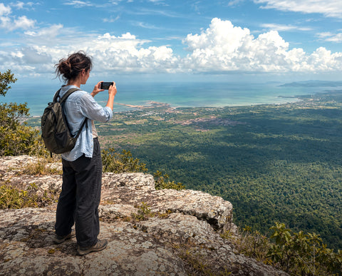 Traveller photographing the coast from a clifftop viewpoint in Cambodia