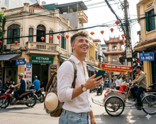 Man with a backpack using an eSIM on a busy street in Vietnam